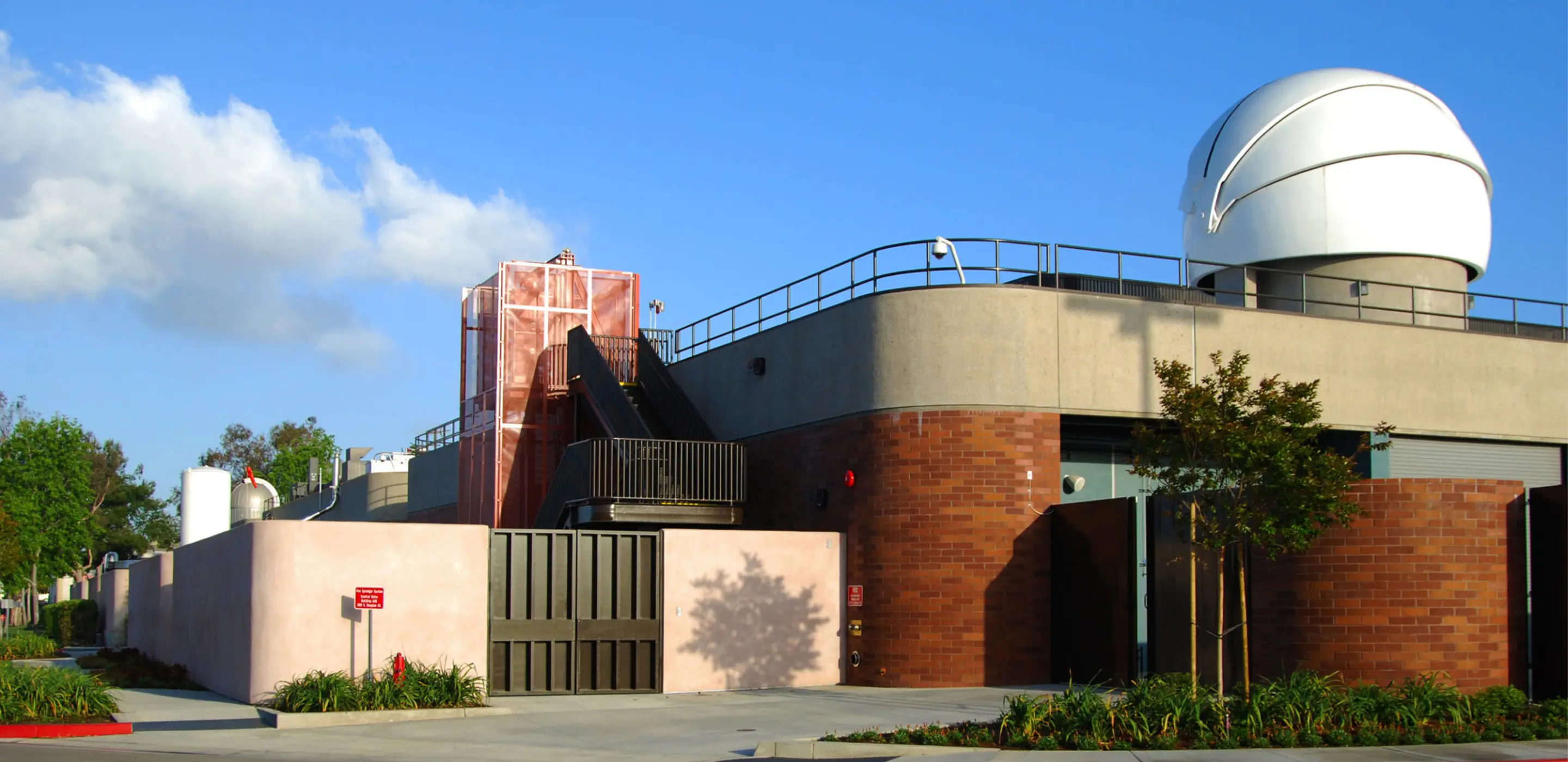 Astronomical observatory building with dome under a clear blue sky.